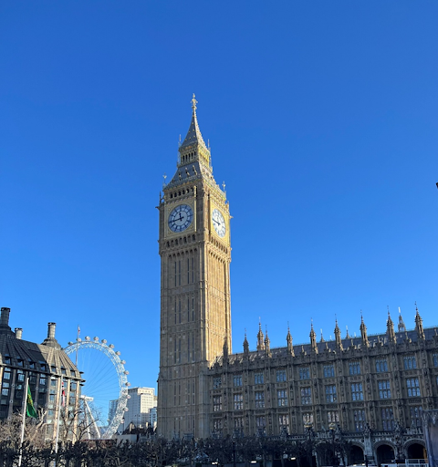 Clock tower and Ferris wheel against blue sky.